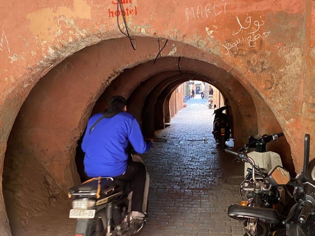 Man on motorcycle driving in arched tunnel in Marrakech souk