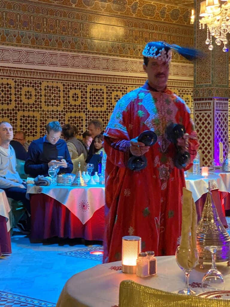 Man with Fez Hat and red caftan and red clanging instrument in Marrakesh Morocco