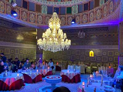 Marrakech restaurant with chandelier and tables with red and white table cloths and intricately tiled walls