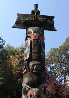 Totem pole traditional Indigenous art with faces carved and painted on a wooden pole