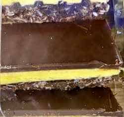 Nanaimo bar with dark chocolate layers and a yellow cream layer in the middle