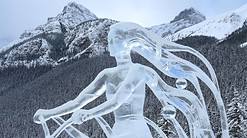 ce carving of woman with flowing ice hair and mountains in the background