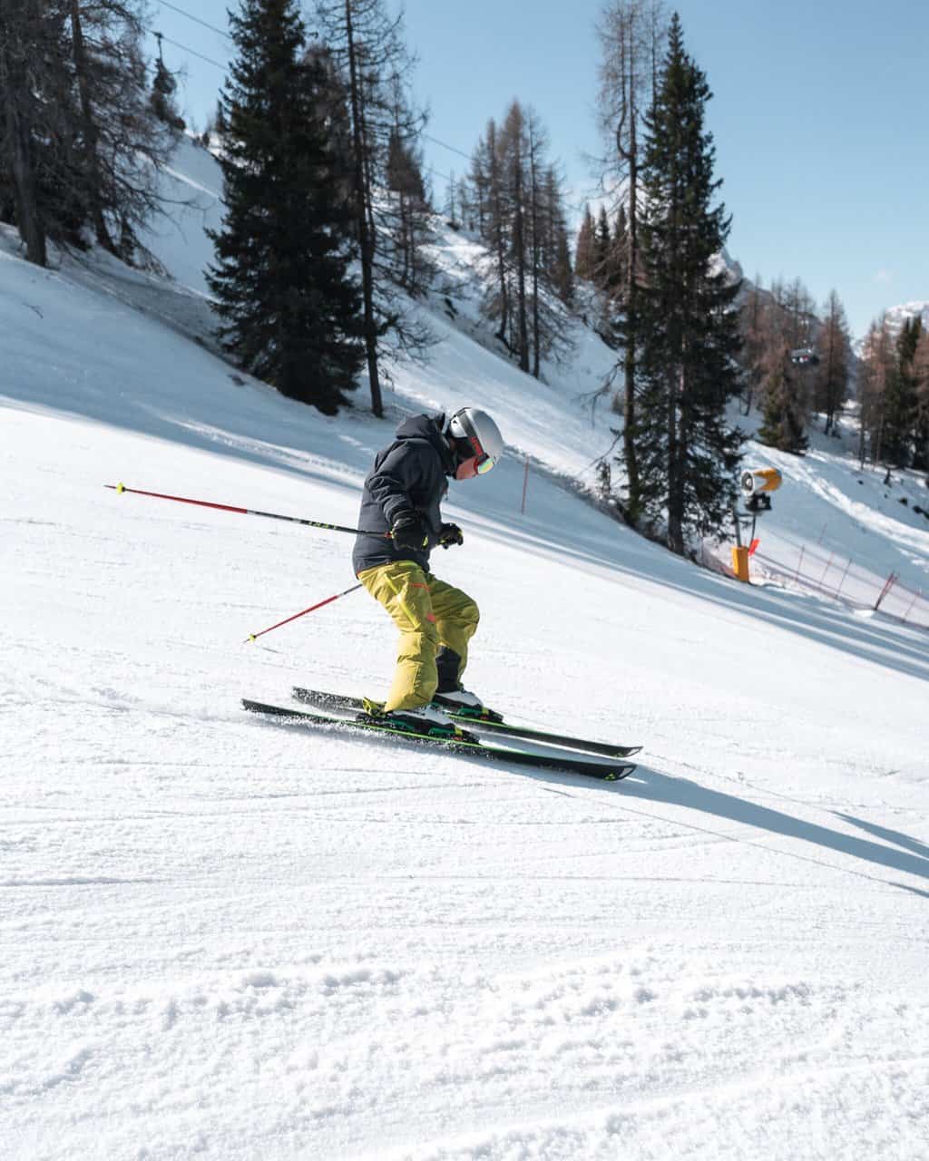 Skier skiing on ski hill with pine trees in bacvkground