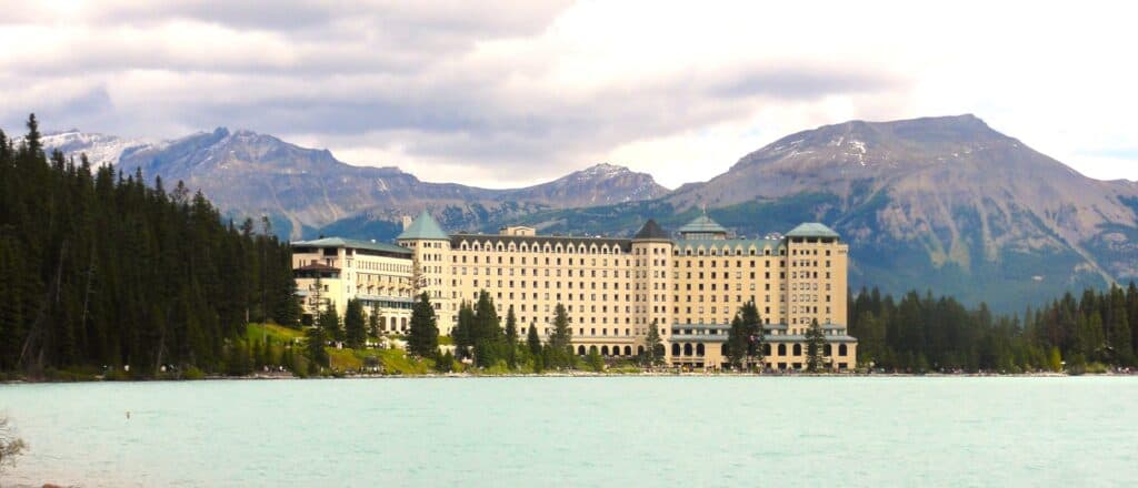 Chateau Lake Louise Hotel with mountains in background and turquoise lake in foreground