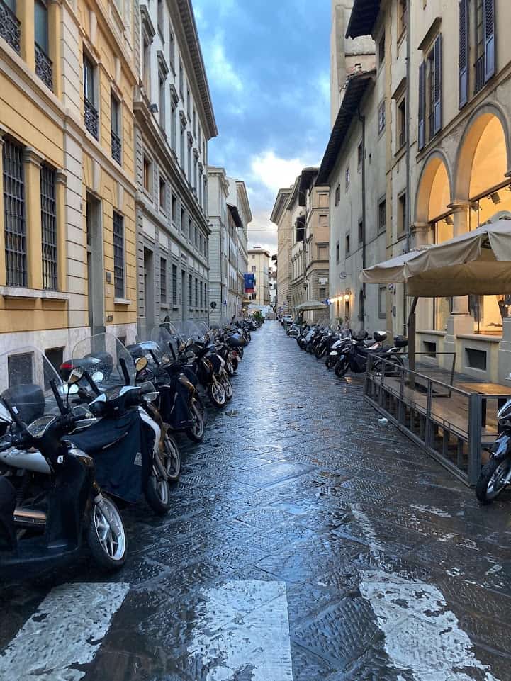 Florence, Italy street  in daylight with buildings and lined with motorcycles 
