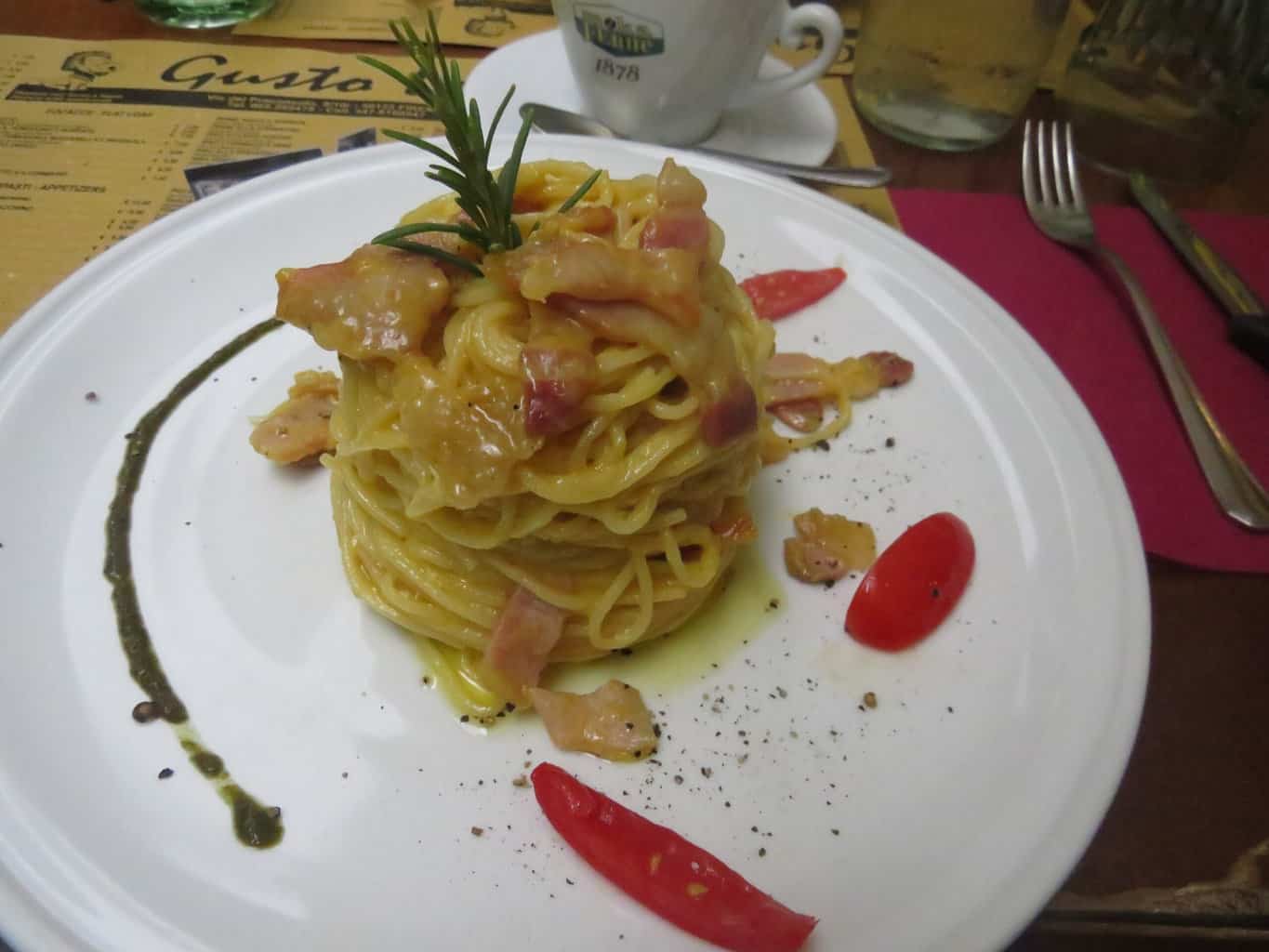 Artfully presented spaghetti pasta with ham and peppers and a sprig of rosemary