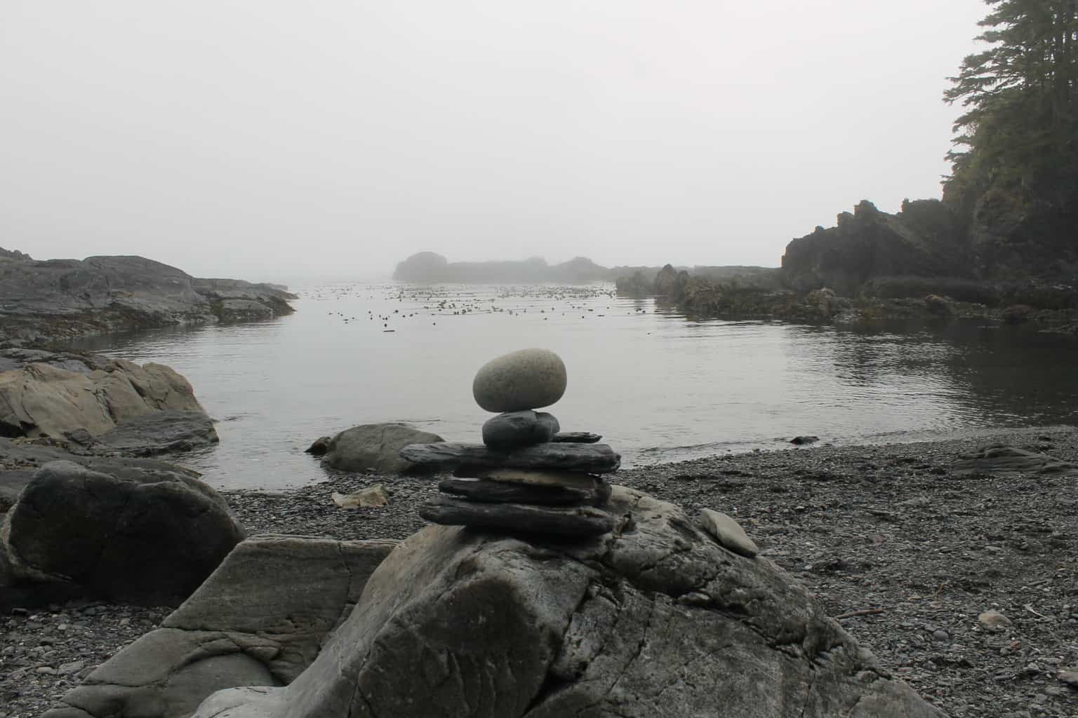 Inukshuk stone pile traditionally used by the Inuit people of Canada on a rocky beach with ocean in the background