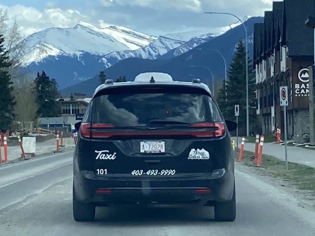 Black Three Sisters Taxi cab in Canmore with mountains in the background