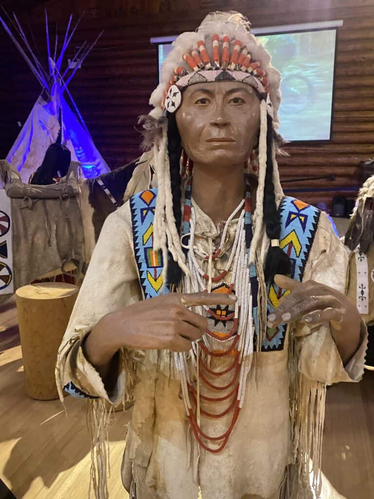 Indigenous man sculpture and tipi in background