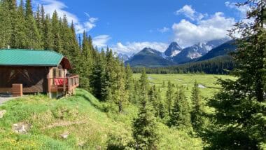Mount Engadine Lodge in summer surrounded by mountain peaks and green grassy meadows