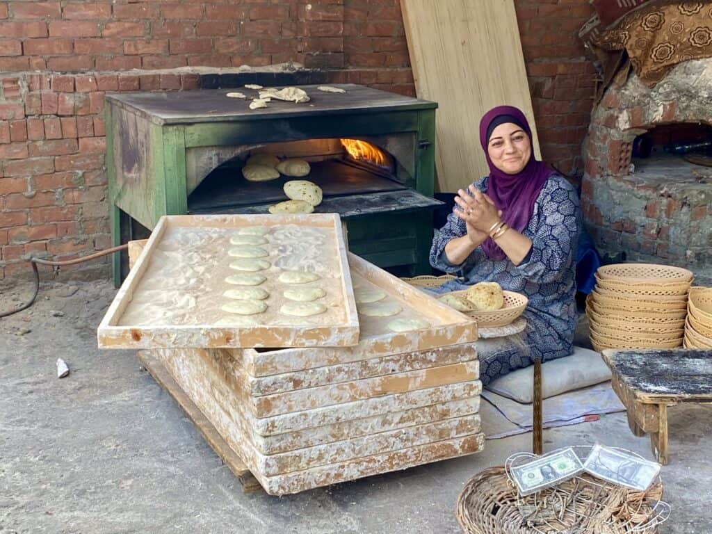 A woman baking fresh pita bread on a stone baked open stove in Egypt